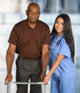 caregiver and senior woman are smiling while walking at the hallway